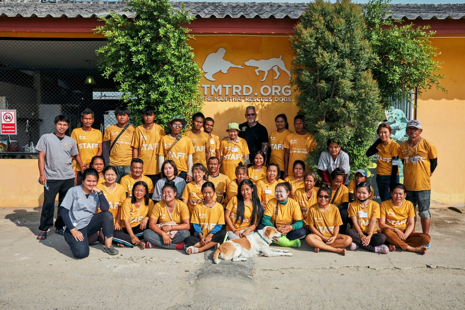 The TMTRD team in orange staff shirts outside the sanctuary’s logo wall