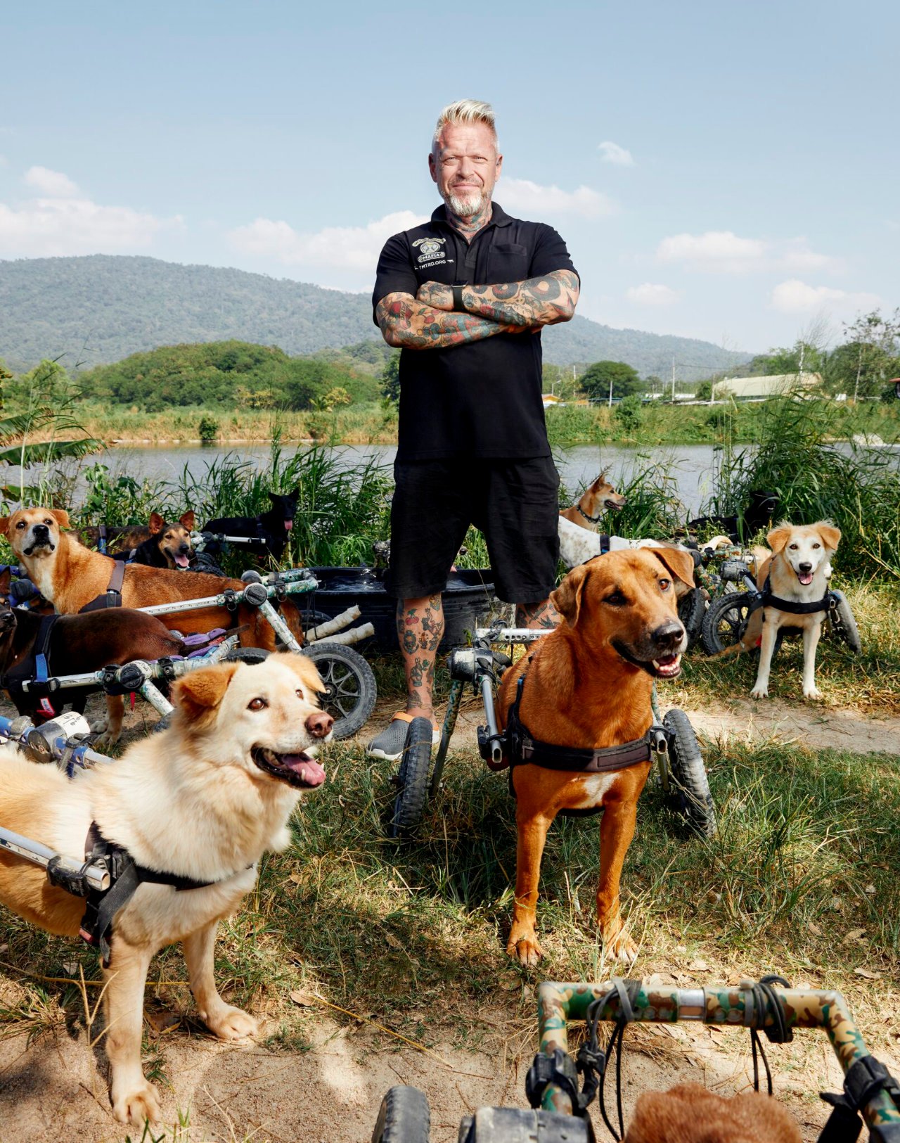Founder Michael Baines standing among rescued dogs in wheelchairs by the river